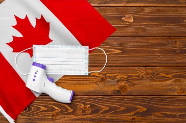 Kanada bayrağında tıbbi maske ve temassız termometre