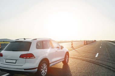 Gün doğumunda boş asfalt yolda beyaz bir çapraz araba.