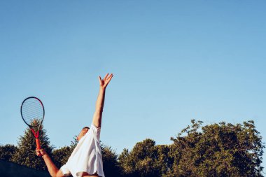 Genç proffesional tenis oyuncusu servis yapıyor.