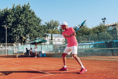 Açık havada tenis oynayan orta yaşlı bir adam dosyalanmış.