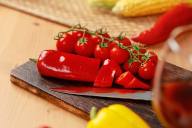 Mutfak tezgahında kiraz domatesli ahşap kesim tahtası ve biber.