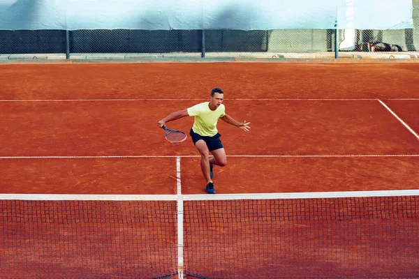 Jeune homme beau jouant au tennis sur le court de tennis — Photo