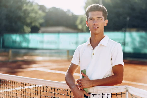 Young mixed race man tennis player with racket standing on tennis court