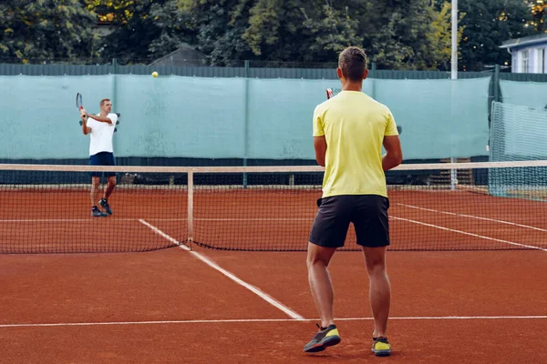 Two men playing tennis on clay tennis field — Stock Photo, Image