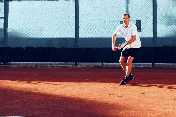 Genç adam sabahları tenis kortunda tenis oynar. — Stok fotoğraf