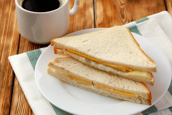 Tosta de sanduíche e xícara de café em guardanapo na mesa de madeira — Fotografia de Stock