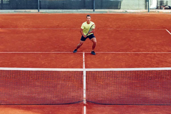 年轻英俊的男子在网球场打网球 — 图库照片