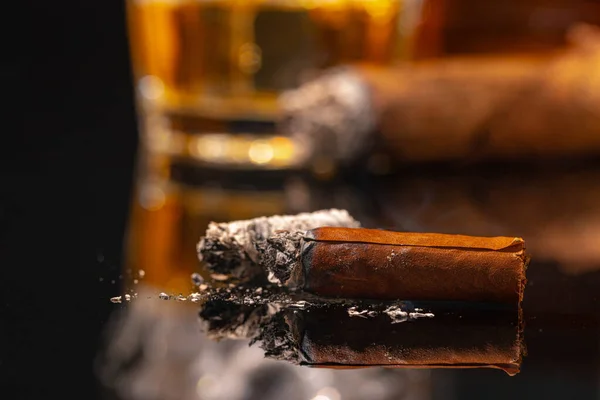 Vaso de whisky y cigarro encendido sobre fondo negro — Foto de Stock