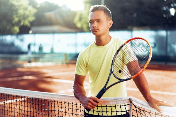 Jovem adolescente com raquete de tênis em pé perto da rede na quadra de barro — Fotografia de Stock