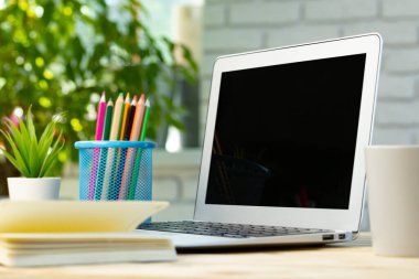 Not defteri ve tahta masadaki kalem yığınıyla bilgisayarı aç