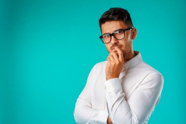 Çenesine dokunan düşünceli genç adamın fotoğrafı.