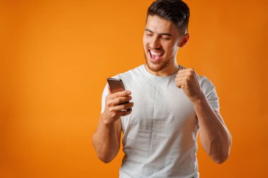 Beyaz gömlekli genç adam akıllı telefonunu kullanıyor.