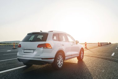 Gün doğumunda boş asfalt yolda beyaz bir çapraz araba.