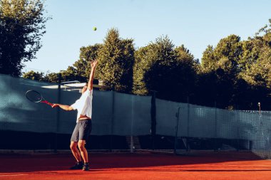 Genç proffesional tenis oyuncusu servis yapıyor.