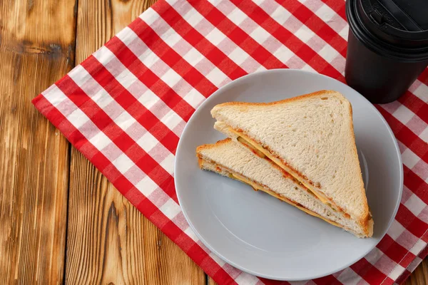 Toast sandwich and cup of coffee on napkin on wooden table — Stock Photo, Image