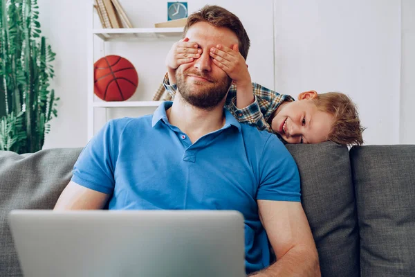 Menino cobre pais olhos com as mãos na sala de estar — Fotografia de Stock