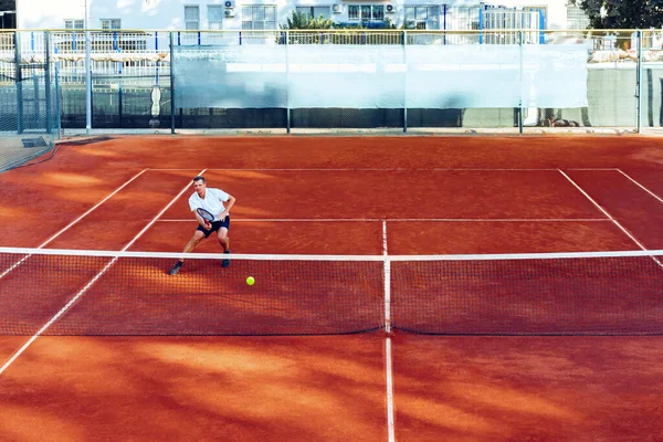 Adam uzaktan, kil tenis sahasında tenis oynuyor. — Stok fotoğraf