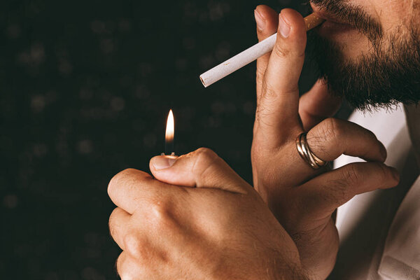 Bearded man lighting cigarette with fire lighter