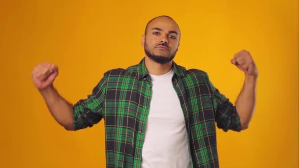 Hombre afroamericano en camisa casual mostrando sus fuertes manos sobre fondo amarillo — Vídeos de Stock