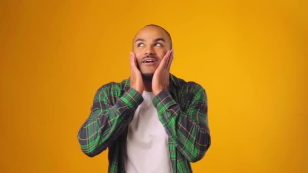 Gelukkig verrast en geschokt Afrikaanse Amerikaanse man tegen gele achtergrond — Stockvideo