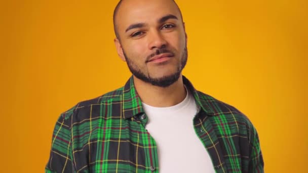 Fiatal afro-amerikai férfi alkalmi ing mosolyog, és emelje fel a szemöldökét sárga háttér — Stock videók