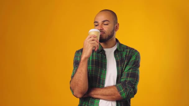 Agréable jeune homme afro-américain buvant du café dans une tasse en papier sur fond jaune — Video