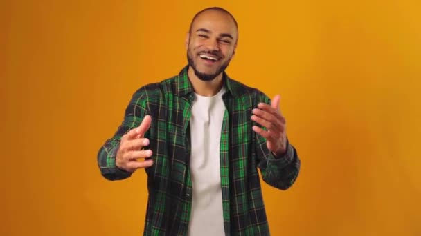 Vriendelijk positief Afrikaans Amerikaanse man verwelkomen u en gebaren "kom hier" tegen gele achtergrond — Stockvideo