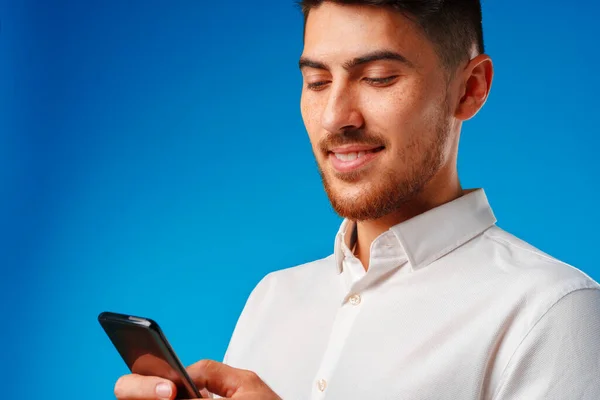 Fiatal férfi fehér ingben használja az okostelefonját — Stock Fotó