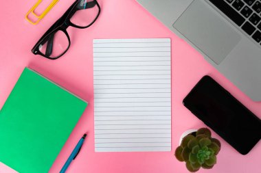 Masadaki dizüstü bilgisayarın ve not defterinin üst görünümü