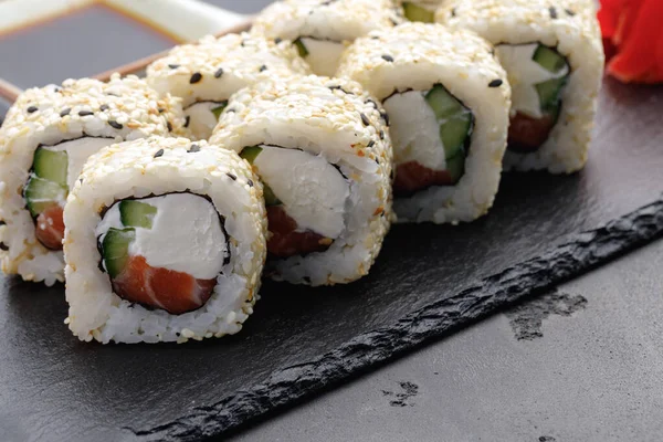 Rolo de sushi com salmão, queijo filadélfia e gergelim no prato de perto — Fotografia de Stock