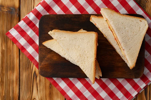 Tahta kesme tahtasında peçeteyle ikiye bölünmüş sandviçler. — Stok fotoğraf