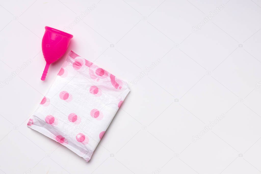 Menstrual cup and hygienic pad on paper background