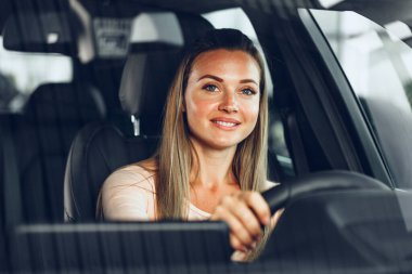 Mutlu bir kadın araba sürüyor ve gülümsüyor.