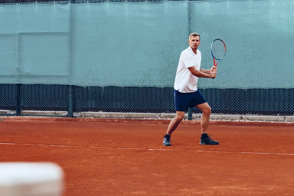 Genç adam sabahları tenis kortunda tenis oynar. — Stok fotoğraf