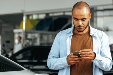 Afrikalı Amerikalı adam akıllı telefonuna bakıyor.