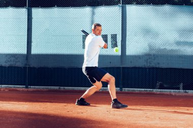 Proffesional tenis oyuncusu maç sırasında topa vuruyor.