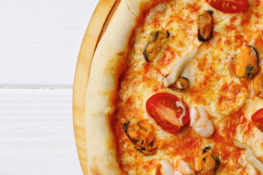 Beyaz ahşap masada deniz ürünleri pizzası.