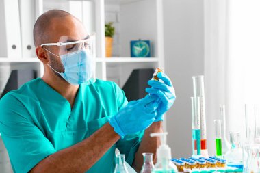 Afro-Amerikalı doktor masada oturuyor ve bir ilaç enjekte etmeye hazırlanıyor.