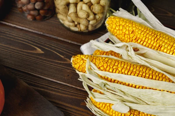 Mazorcas de maíz sobre mesa de madera marrón oscuro — Foto de Stock