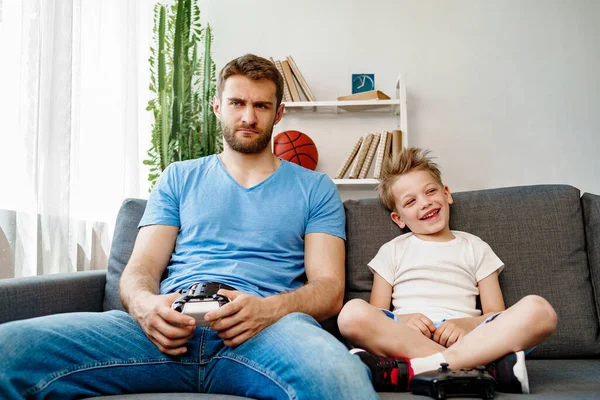 Padre y su pequeño hijo jugando videojuegos juntos en casa — Foto de Stock