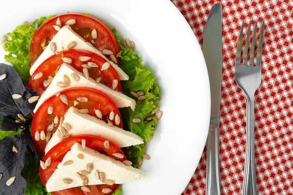Salat mit frischen Tomaten und gesalzenem Käse, Sonnenblumenkerne obendrauf — Stockfoto