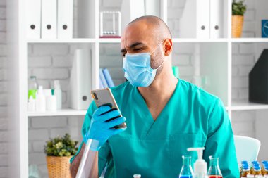 İş yerinde akıllı telefonunu kullanan Afrikalı Amerikalı doktor ya da laboratuvar çalışanı.