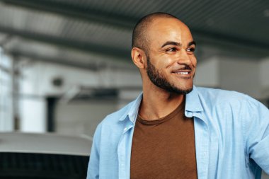 Gülümseyen Afro-Amerikan adam gülümsüyor ve yanına bakıyor.