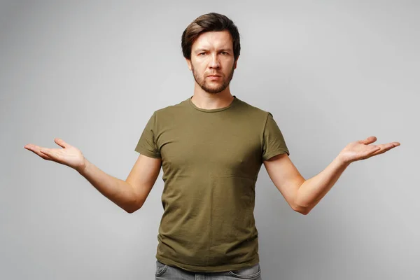 Ahnungsloser junger Mann gestikuliert "ich weiß nicht" vor grauem Hintergrund — Stockfoto