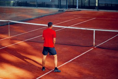 Tenis kortunda oynayan bir adamın arka görünüşü