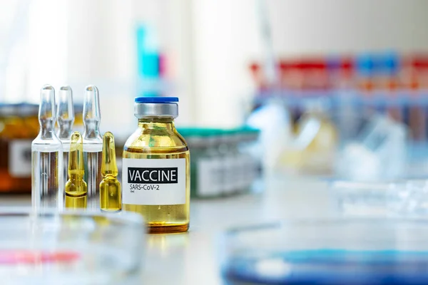 실험실 배경에서 탁자 위에 주사용 유리병에 주사하는 백신 — 스톡 사진