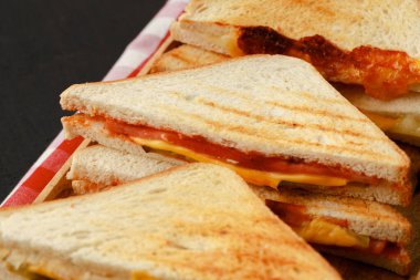 Tahta kesme tahtasında peçeteyle ikiye bölünmüş sandviçler.