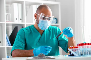 Afrikalı Amerikalı doktor veya laboratuvar çalışanı klinikte kan örneğini inceler.