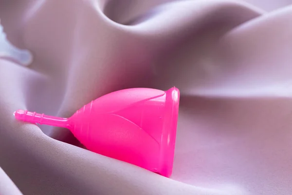 Менструальна чашка на рожевій шовковій тканині крупним планом — стокове фото