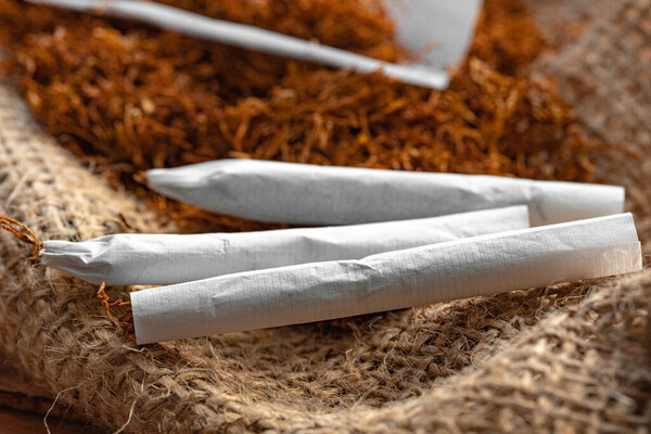 Сигаретная бумага и куча табака на деревянном столе